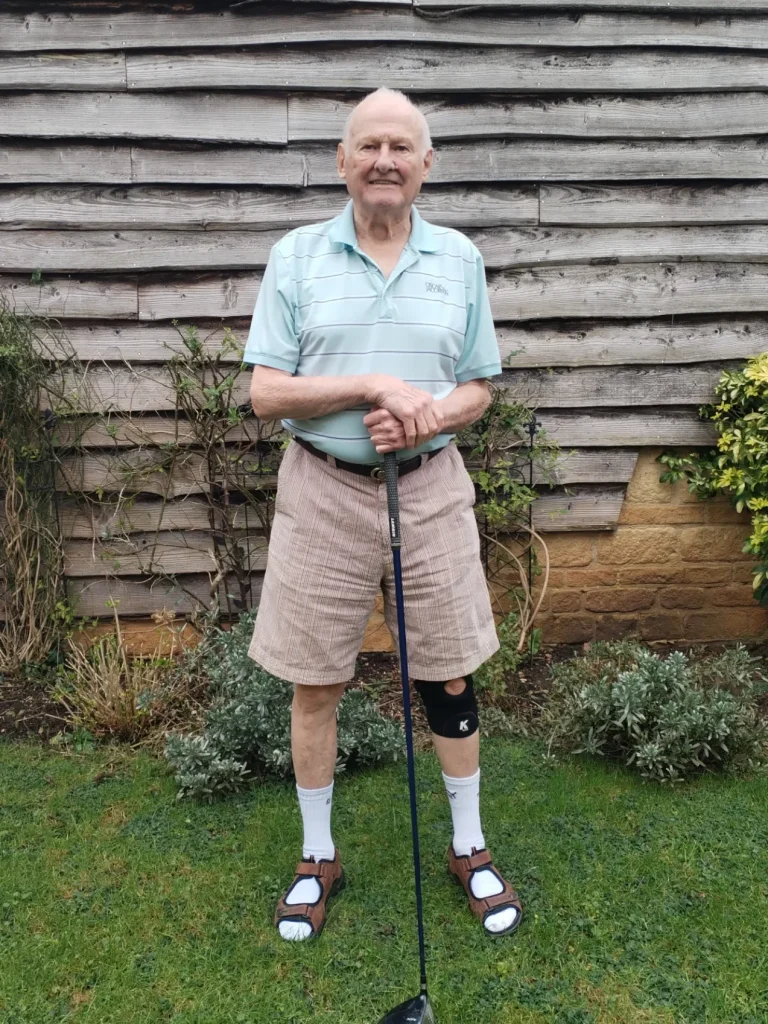 Knee brace being worn by elderly man holding golf club