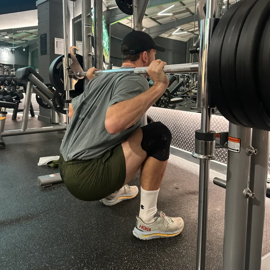 Knee brace being worn by man performing deep squat